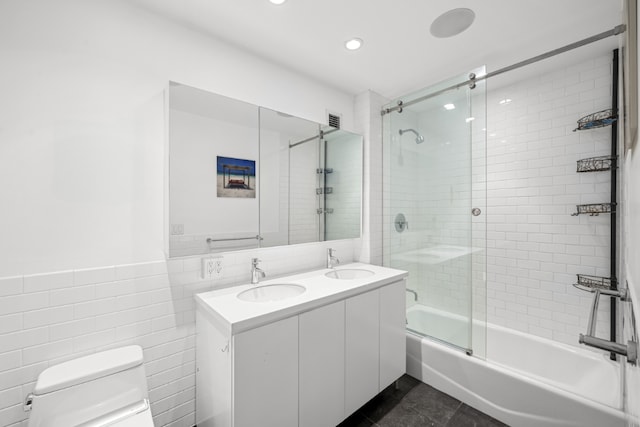 full bathroom with tile patterned floors, toilet, combined bath / shower with glass door, tile walls, and vanity