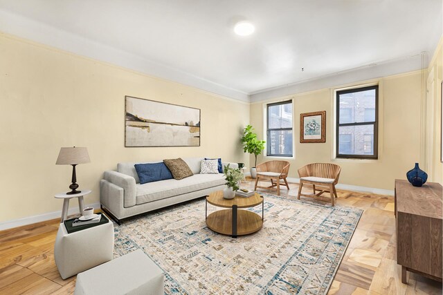 living room featuring light wood-style flooring, baseboards, and crown molding