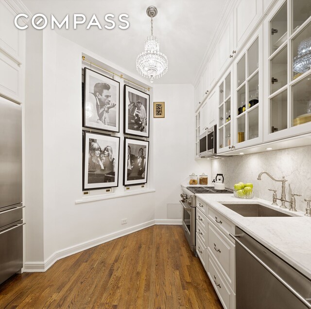 kitchen featuring backsplash, a chandelier, premium appliances, white cabinets, and a sink