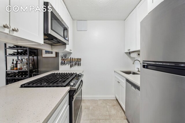 kitchen featuring stainless steel appliances, sink, a textured ceiling, and white cabinets