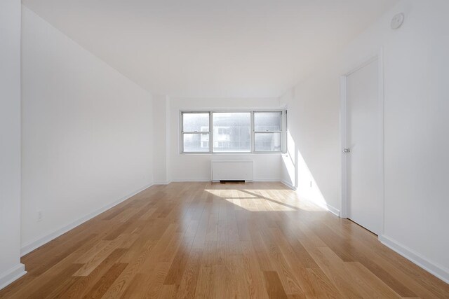 empty room with radiator heating unit and light hardwood / wood-style floors