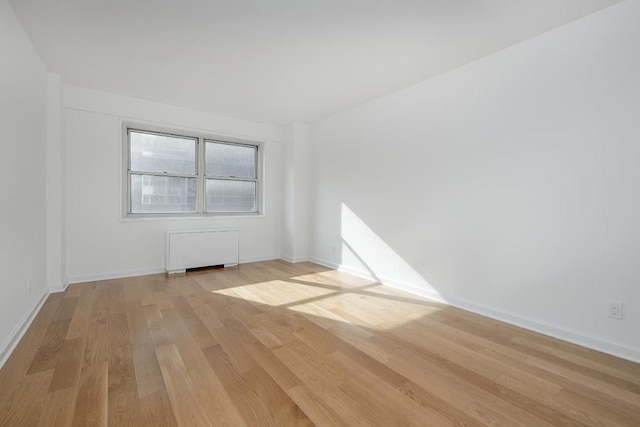 spare room with radiator and light hardwood / wood-style floors