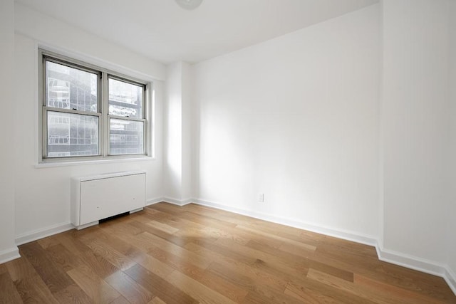 empty room featuring radiator heating unit and light hardwood / wood-style floors