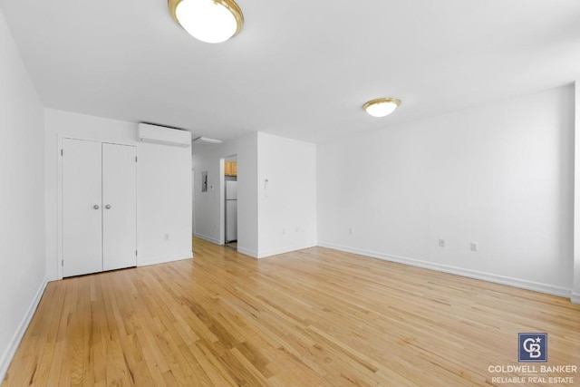 spare room with a wall unit AC and light hardwood / wood-style floors