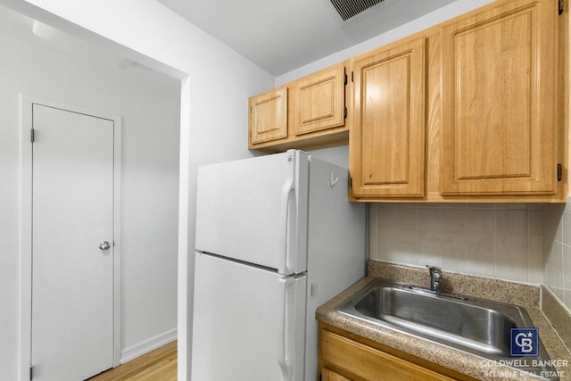 kitchen featuring white refrigerator, sink, light brown cabinets, and backsplash