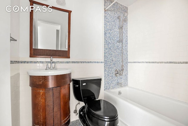 full bathroom with vanity, toilet, tiled shower / bath combo, and tile walls