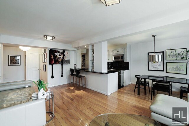 living area with a notable chandelier, light wood-style flooring, and baseboards