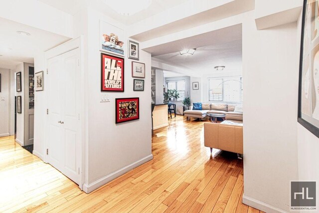 hallway featuring light wood finished floors and baseboards