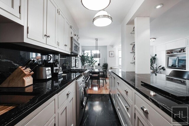 kitchen with stainless steel microwave, backsplash, washer / dryer, dark stone countertops, and white cabinets