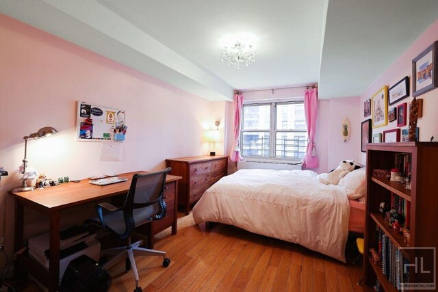 bedroom with light wood-style flooring and a chandelier