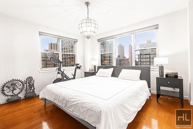 bedroom featuring a city view, multiple windows, and wood-type flooring