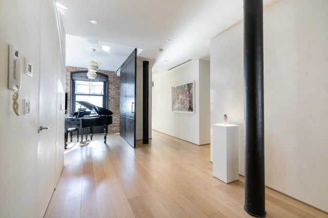 corridor featuring light wood-style floors and brick wall