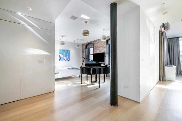 interior space with visible vents, brick wall, and wood finished floors