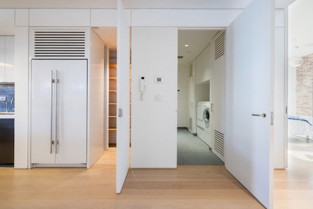 hall with washing machine and dryer and light hardwood / wood-style flooring