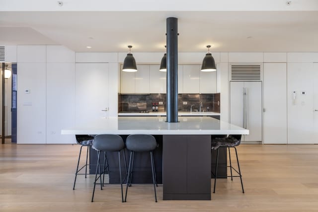 kitchen with decorative light fixtures, built in fridge, white cabinets, and a kitchen island