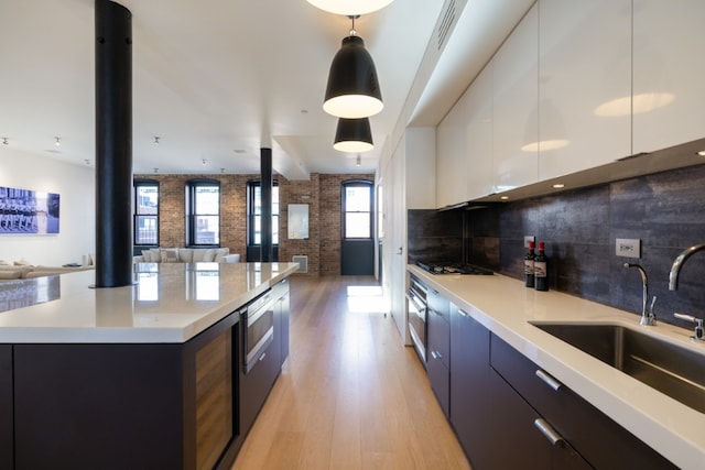 kitchen featuring sink, white cabinetry, a center island, hanging light fixtures, and black gas cooktop