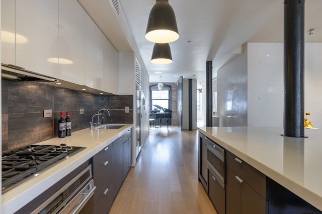 kitchen featuring white cabinetry, hanging light fixtures, stainless steel appliances, and sink