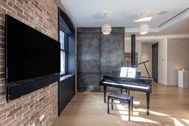 miscellaneous room with brick wall and light wood-type flooring