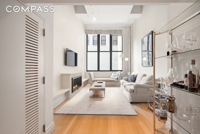 living area featuring beam ceiling, wood finished floors, and a fireplace