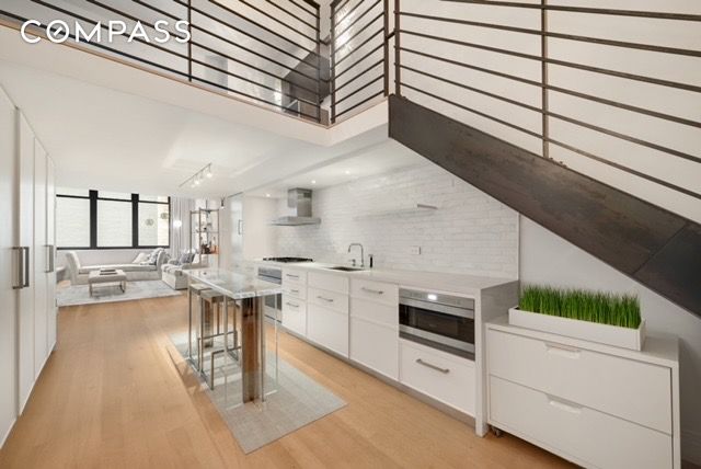 421 Hudson St Unit 320, New York City, NY 10014 - kitchen featuring stainless steel appliances, modern cabinets, wall chimney exhaust hood, light wood-style floors, and white cabinets