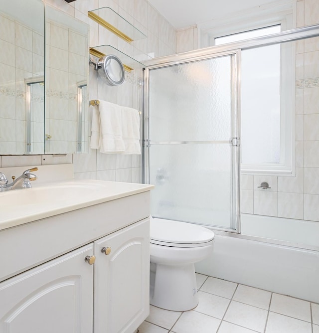 full bathroom featuring vanity, toilet, shower / bath combination with glass door, tile walls, and tile patterned floors
