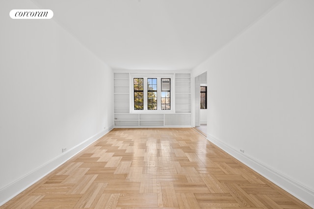 empty room featuring built in features, visible vents, and baseboards