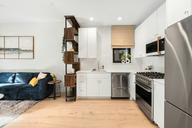 kitchen featuring sink, stainless steel appliances, white cabinets, and light wood-type flooring