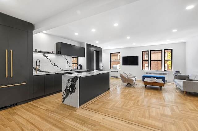 kitchen with tasteful backsplash, radiator heating unit, a center island, and light parquet floors