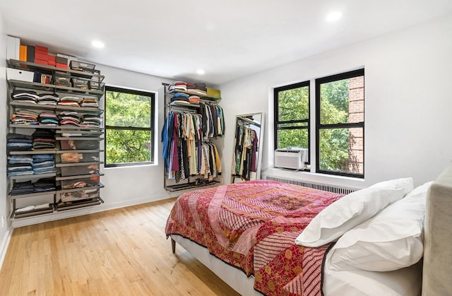 bedroom featuring cooling unit, hardwood / wood-style flooring, and radiator heating unit