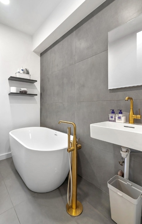 bathroom with tile walls, tile patterned flooring, and a bathing tub