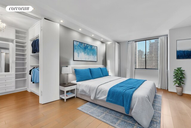 bedroom featuring a walk in closet, hardwood / wood-style floors, and an inviting chandelier