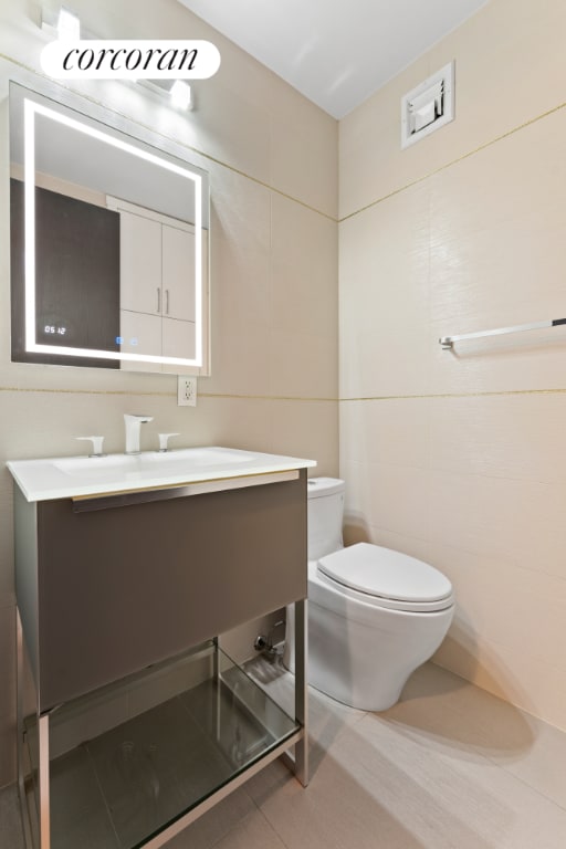 bathroom featuring vanity, tile patterned floors, tile walls, and toilet