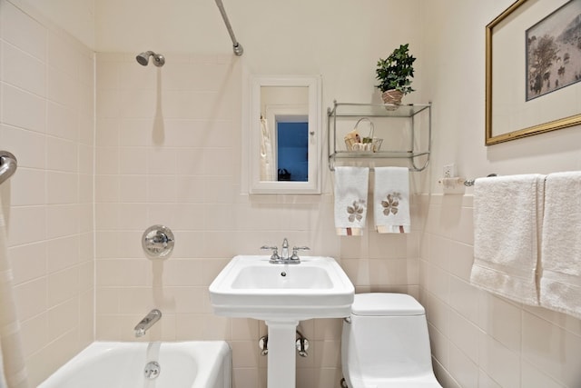 bathroom featuring tile walls, tiled shower / bath combo, and toilet