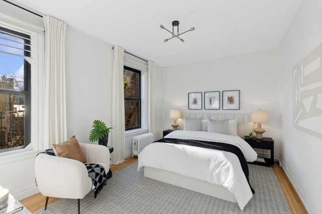 bedroom with radiator heating unit and light hardwood / wood-style floors