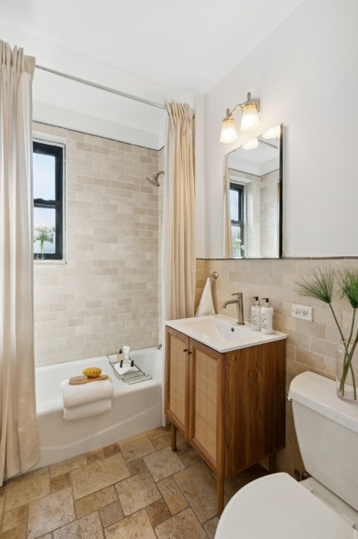 full bathroom featuring vanity, toilet, shower / tub combo, and tile walls