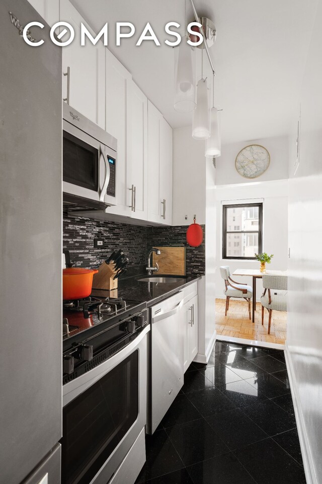 kitchen with a sink, tasteful backsplash, dark countertops, granite finish floor, and appliances with stainless steel finishes