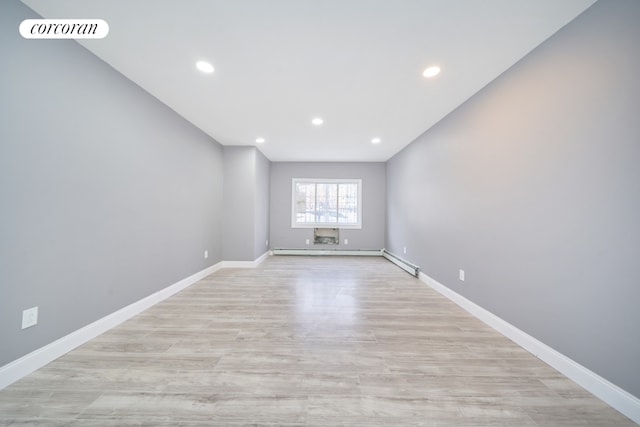 empty room featuring baseboard heating and light wood-type flooring