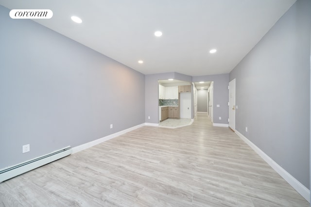 unfurnished living room with a baseboard heating unit and light hardwood / wood-style floors