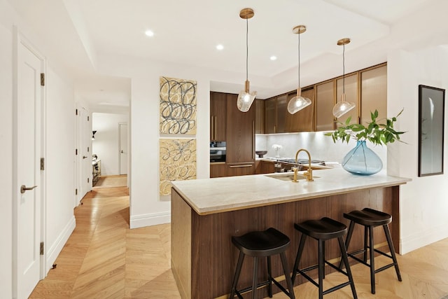 kitchen featuring pendant lighting, kitchen peninsula, light parquet flooring, and a breakfast bar