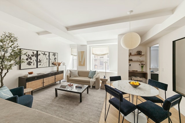 living area with beamed ceiling and light wood-style floors