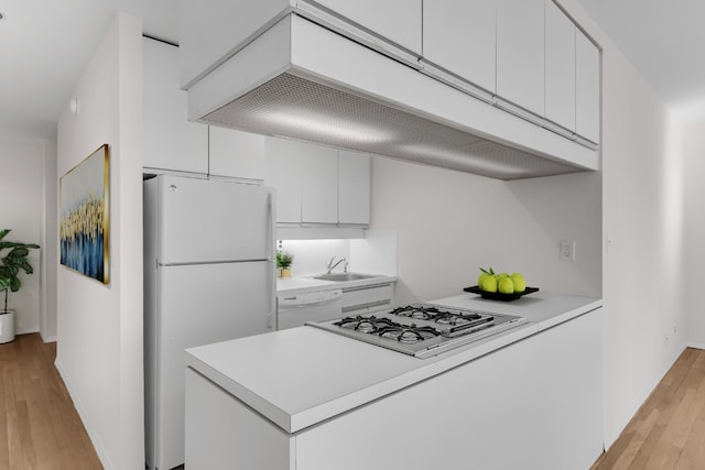 kitchen with white cabinetry, sink, white appliances, and light wood-type flooring