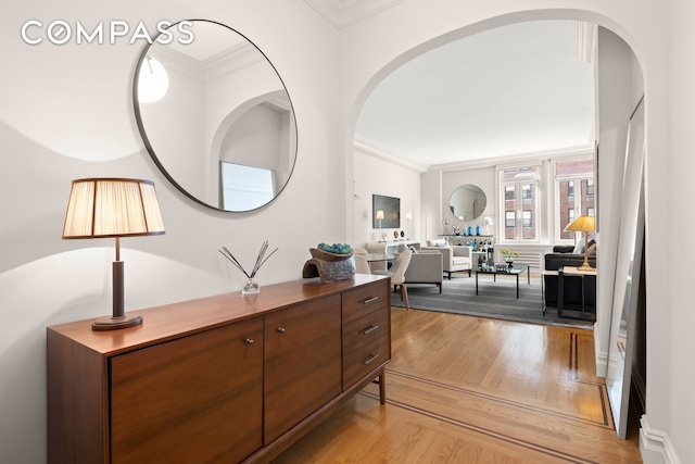 corridor with light wood finished floors and crown molding