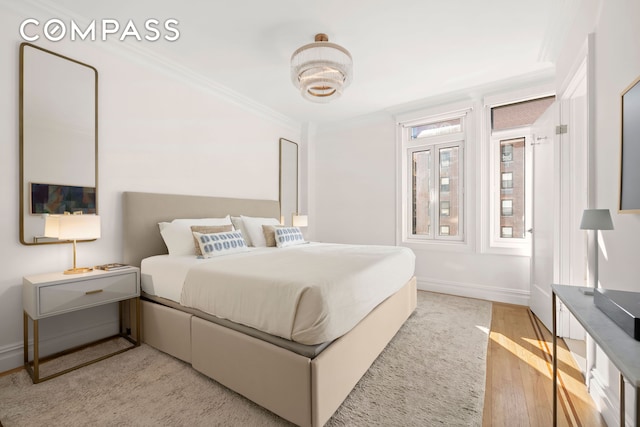 bedroom featuring light wood-style floors, crown molding, and baseboards