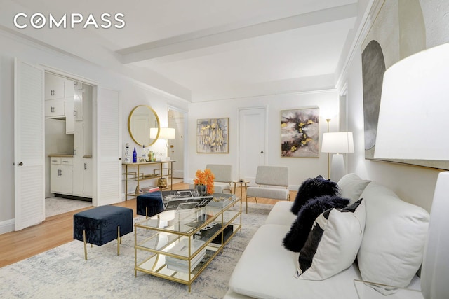 living room featuring beamed ceiling, baseboards, and wood finished floors