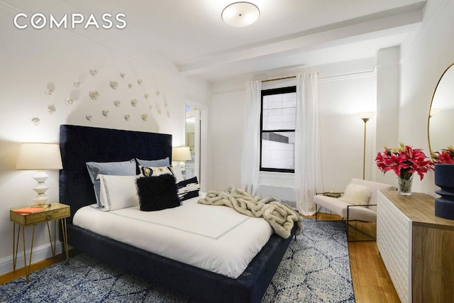 bedroom featuring beamed ceiling and light hardwood / wood-style floors