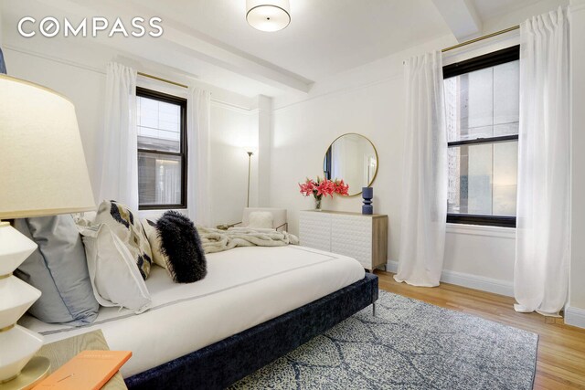 bedroom with beamed ceiling and hardwood / wood-style flooring