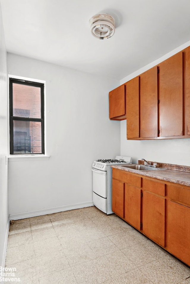 kitchen featuring brown cabinets, white range with gas cooktop, and light floors