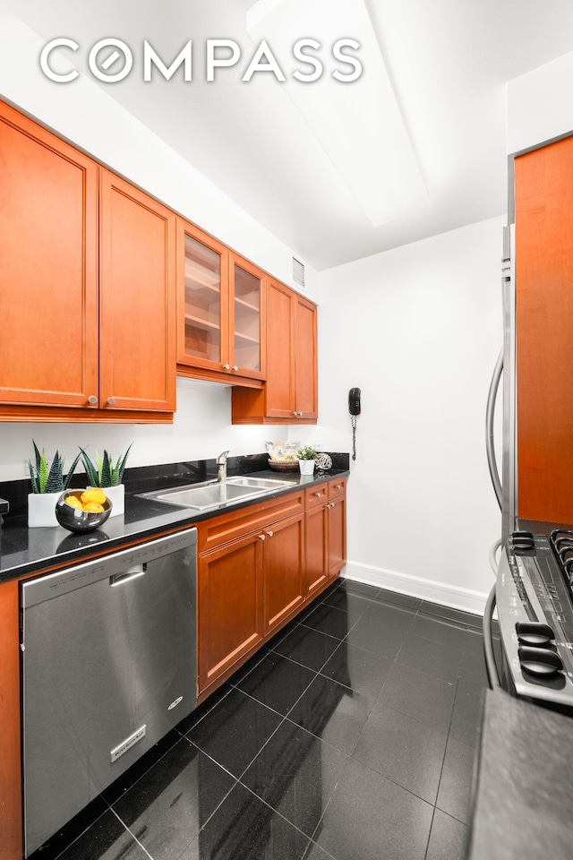 kitchen with dark countertops, dishwasher, dark tile patterned floors, and a sink