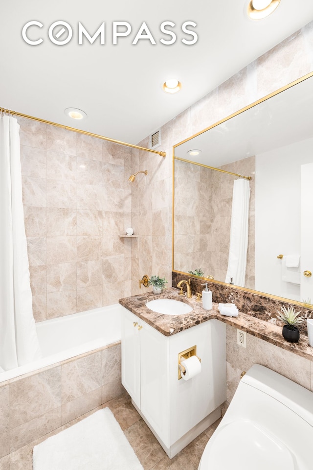 full bath with visible vents, vanity, recessed lighting, tiled shower / bath combo, and tile walls