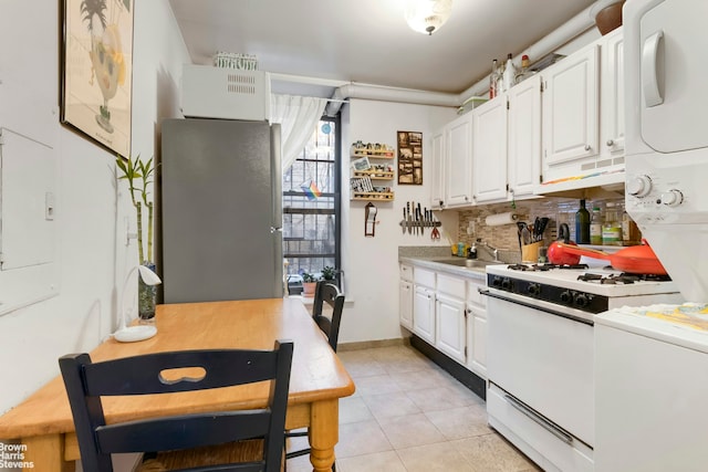 kitchen featuring white gas stove, tasteful backsplash, white cabinetry, and light tile patterned floors